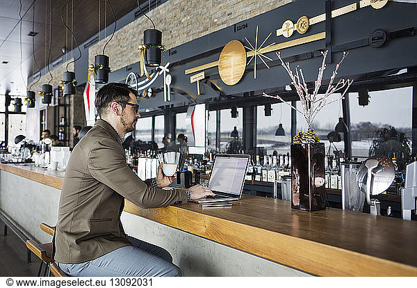 Businessman working on laptop at cafe counter