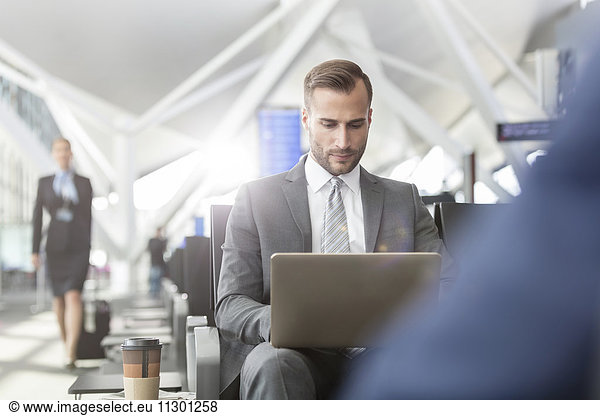 Businessman working using laptop in airport departure area