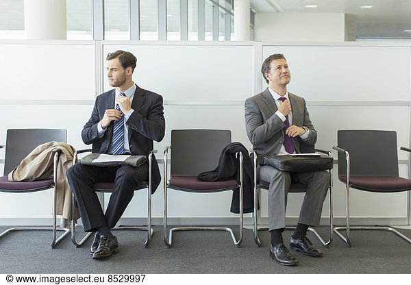 Businessmen adjusting ties in waiting area