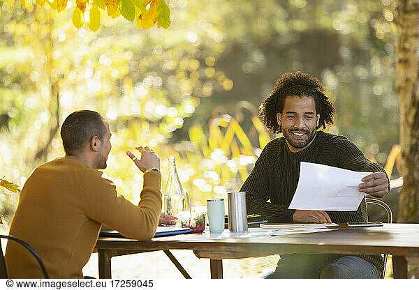 Businessmen discussing paperwork at table in autumn park