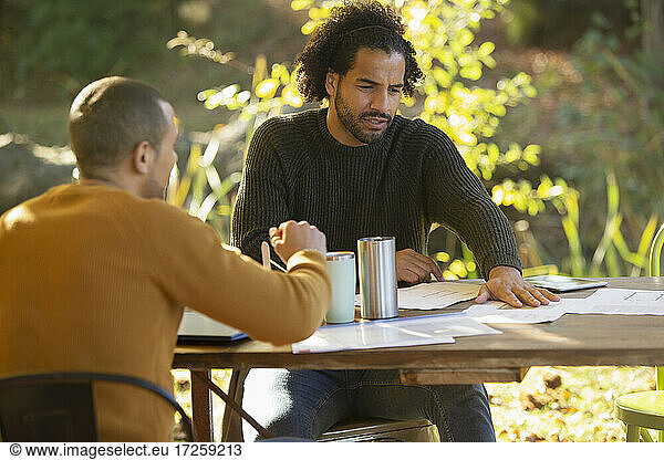 Businessmen discussing paperwork at table in park