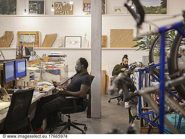 Businessmen eating lunch at desks in open plan office