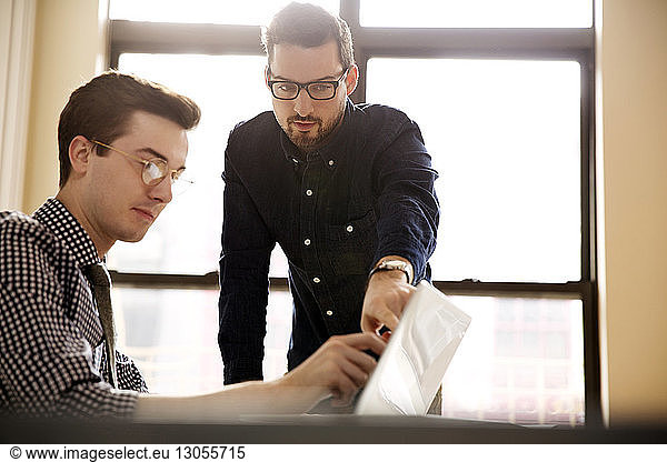 Businessmen having discussion over laptop in office