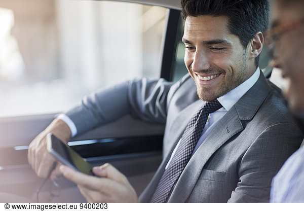 Businessmen looking at cell phone in car