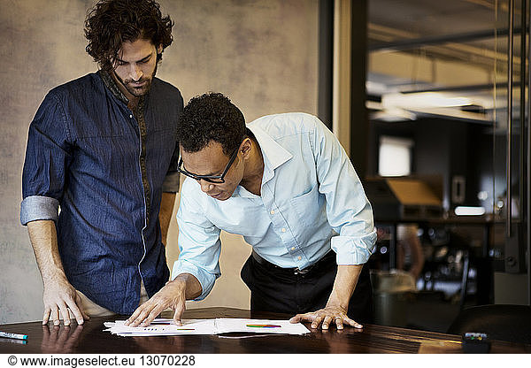 Businessmen looking at document while standing in office