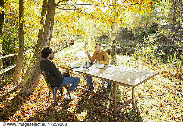 Businessmen meeting at table in sunny idyllic autumn park