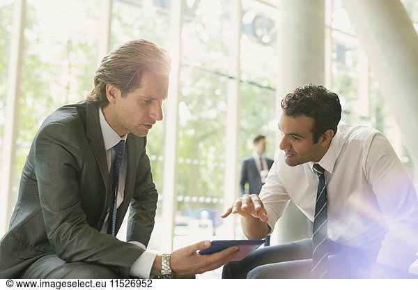 Businessmen meeting using digital tablet in office lobby