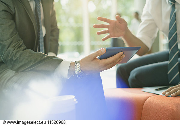 Businessmen meeting using digital tablet  talking and gesturing