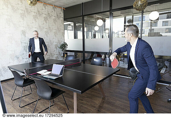 Businessmen playing table tennis at office