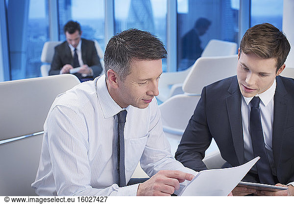 Businessmen reviewing paperwork in office