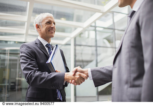 Businessmen shaking hands in office building