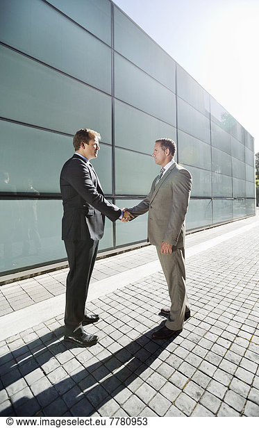 Businessmen shaking hands on city street