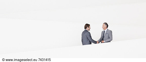 Businessmen shaking hands on modern staircase