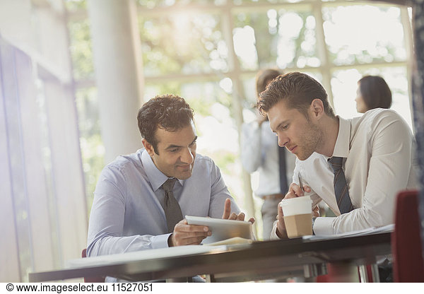 Businessmen using digital tablet at office table