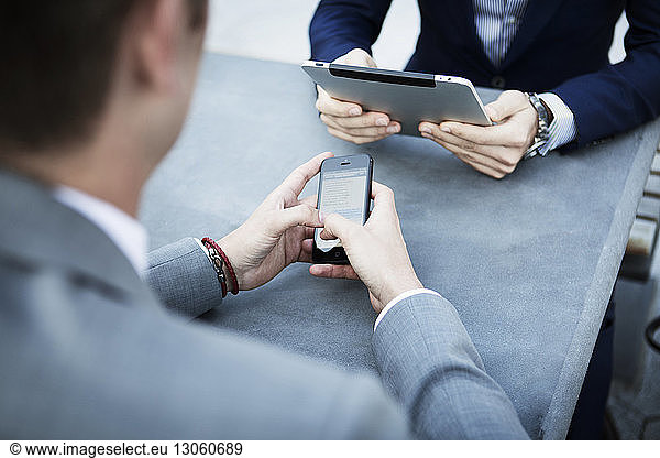 Businessmen using technologies while sitting at table