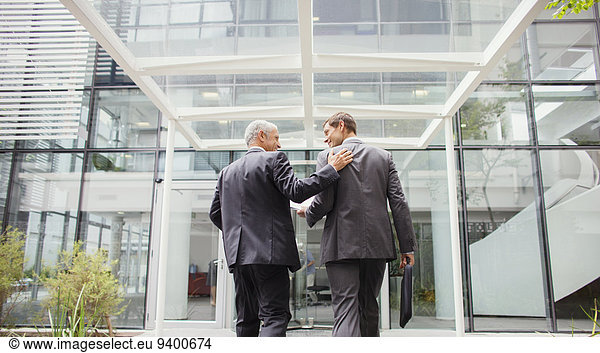 Businessmen walking into office building together