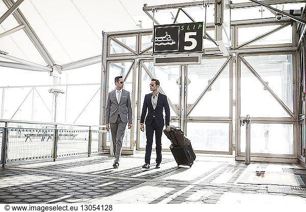 Businessmen with luggage walking in transportation building
