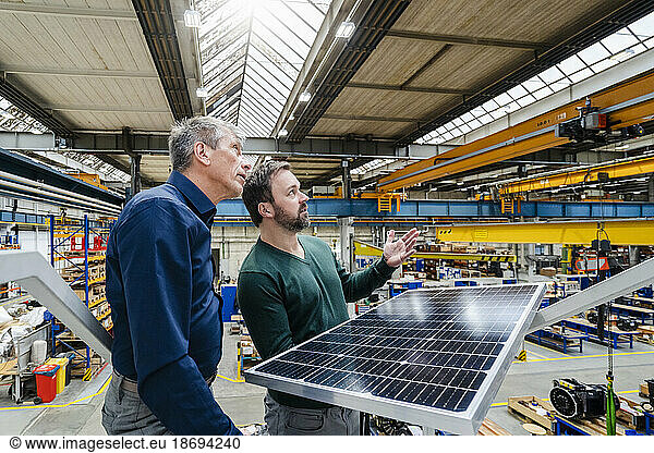 Businessmen with solar panel having discussion in factory