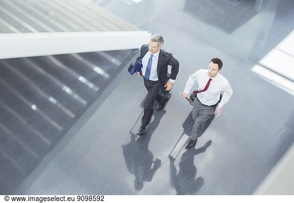 Businessmen with suitcases running in lobby
