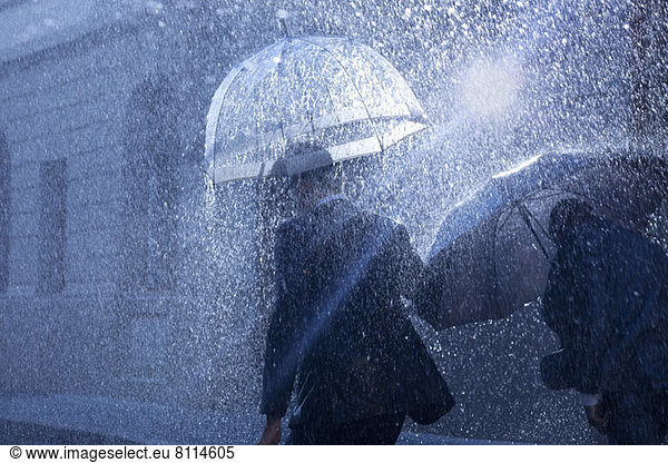 Businessmen with umbrellas in rain