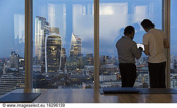 Businessmen working late at highrise office window  London  UK