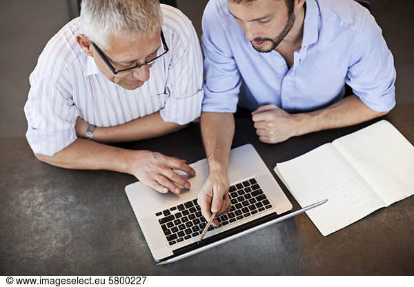 Businessmen working on laptop together