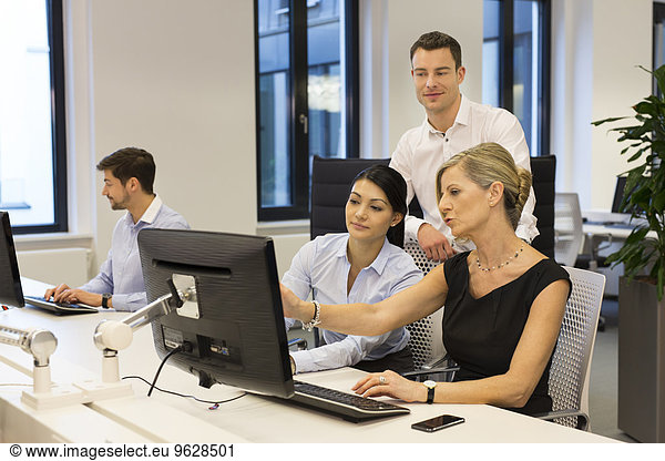 Businesspeople at desk looking at computer monitor
