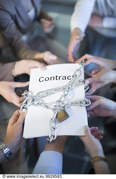 Businesspeople holding contract locked with chain