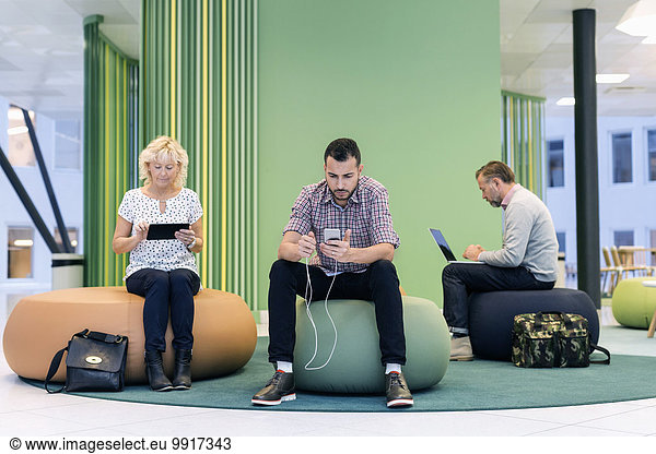 Businesspeople using technologies at modern office lobby