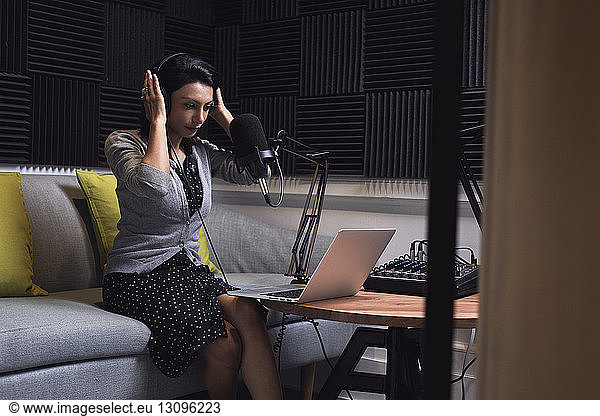 Businesswoman adjusting headphones while video conferencing in office