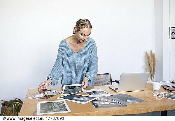 Businesswoman analyzing photographs on table at home