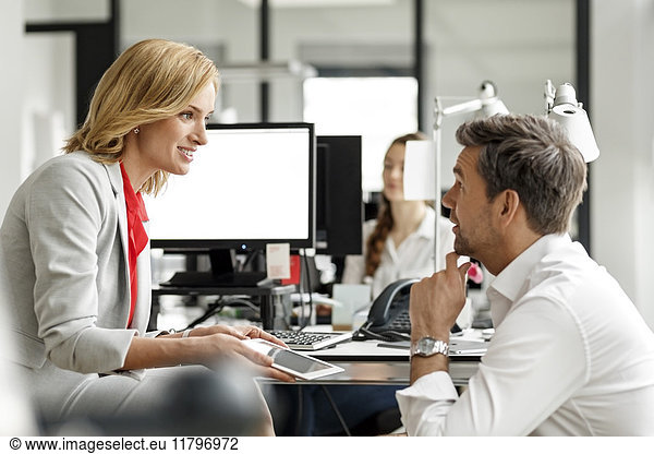 Businesswoman and businessman discussing at desk in office