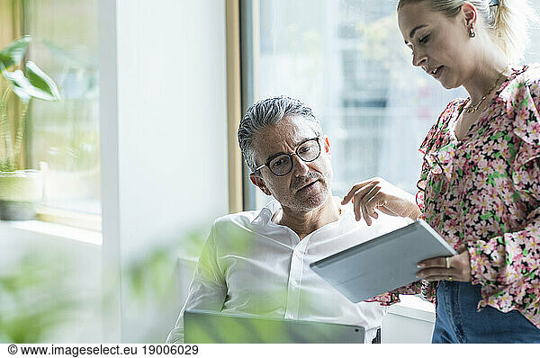 Businesswoman and businessman discussing over tablet PC in office