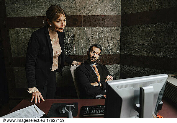 Businesswoman and businessman staring at computer monitor at law office