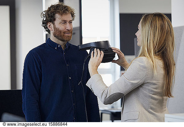 Businesswoman and businessman with VR glasses talking in office
