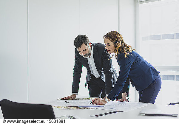 Businesswoman and businessman working on plan on desk in office