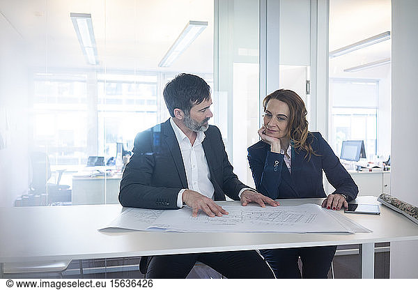 Businesswoman and businessman working on plan on desk in office