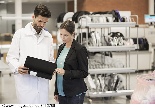 Businesswoman and engineer looking at file in manufacturing plant