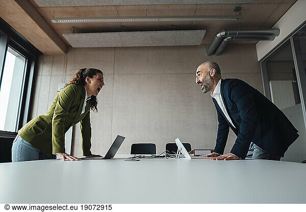 Businesswoman arguing with businessman at desk in office