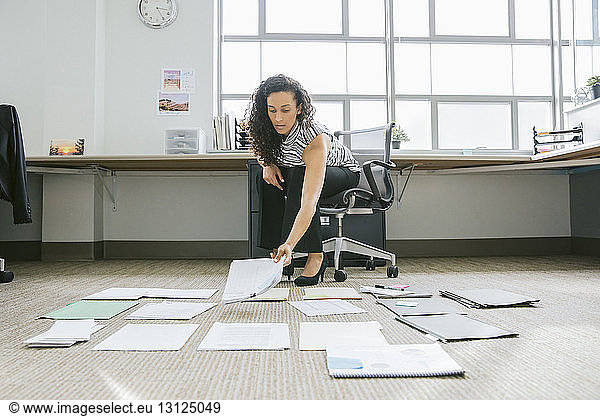 Businesswoman arranging documents on floor in office