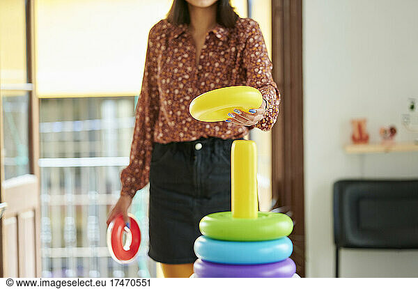 Businesswoman arranging multi colored ring toy in office