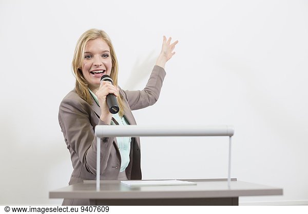 Businesswoman at speakers desk in auditorium