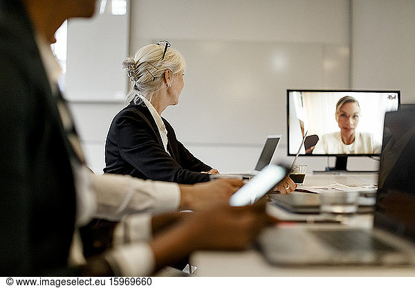 Businesswoman attending video conference with colleagues in meeting at office