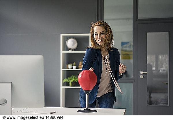 Businesswoman boxing a punchingball in her office