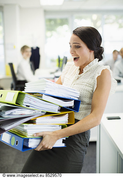 Businesswoman carrying folders in office
