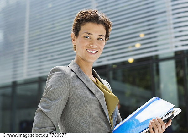 Businesswoman carrying folders outdoors