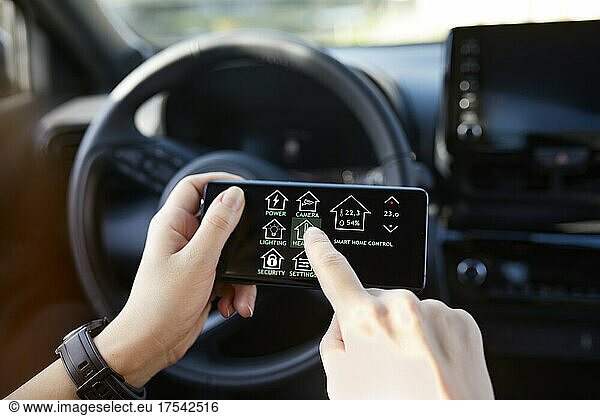 Businesswoman controlling smart house through mobile phone while sitting in car