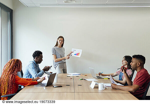 Businesswoman discussing over report with colleagues in meeting at office