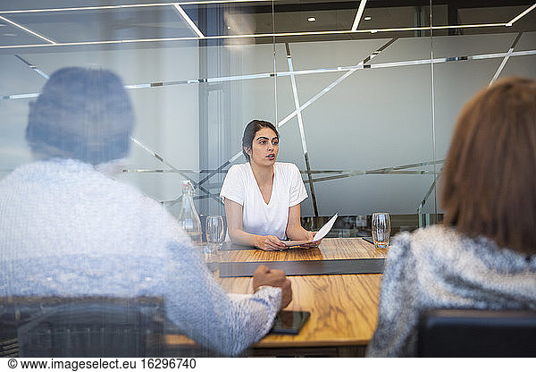 Businesswoman discussing paperwork in conference room meeting