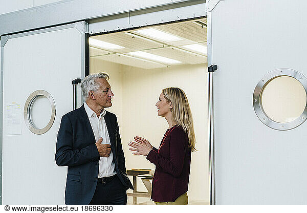 Businesswoman discussing with businessman standing at doorway